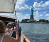 Passengers on a sailboat are capturing photos of the Statue of Liberty on a sunny day
