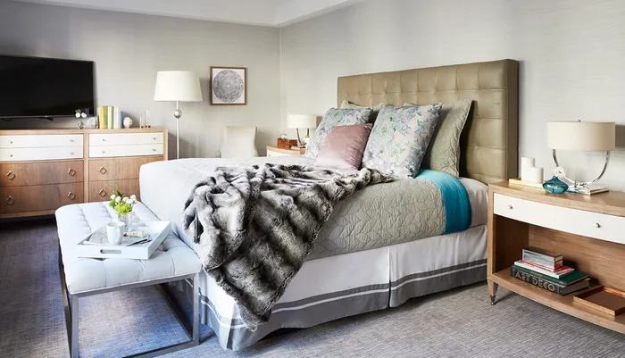A well-appointed bedroom featuring a neatly made bed with a tufted headboard coordinating pillows a plush throw modern furniture and decorative accents creating a luxurious and cozy atmosphere