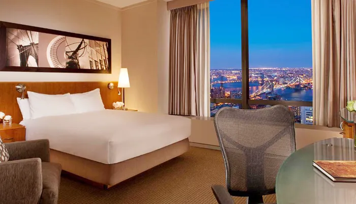 A hotel room with a large bed tasteful decor and a stunning night view of a cityscape through the window