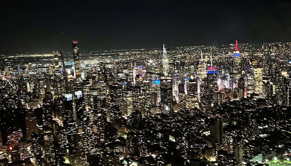 The image displays a panoramic night view of a densely illuminated cityscape with numerous skyscrapers and the characteristic glow of urban lights