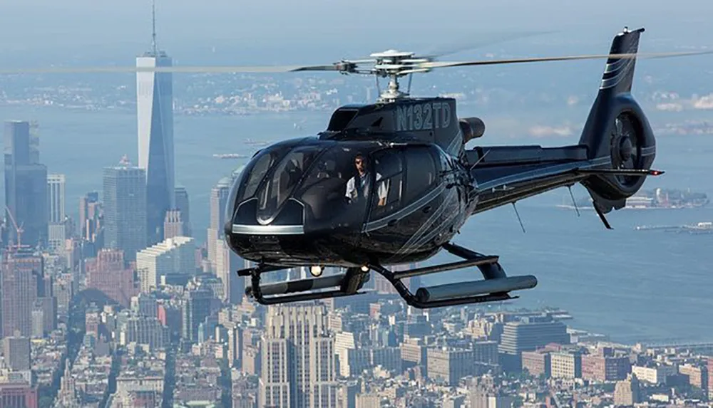 A helicopter with passengers on board is flying over an urban cityscape with skyscrapers in the background