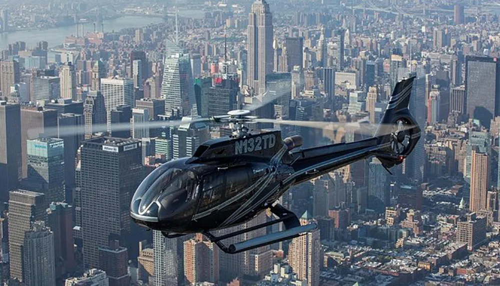 A helicopter is flying over a densely built urban area showcasing a citys skyline in the background