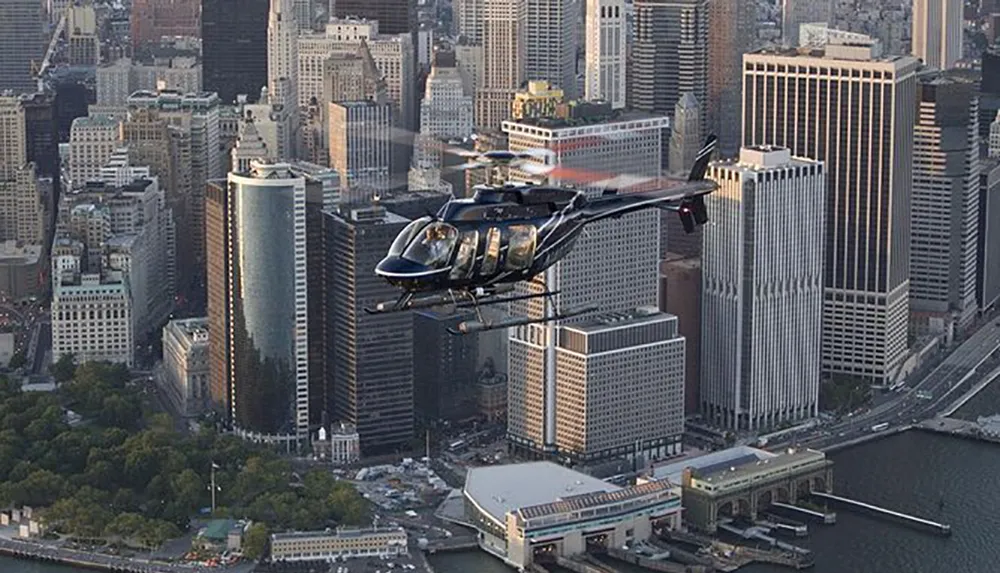 A helicopter is flying over a dense urban landscape with skyscrapers and a body of water visible below