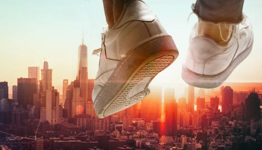 A pair of shoes against a city skyline with the impression of someone jumping or floating above the urban landscape at sunset