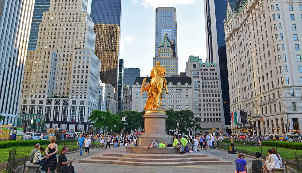 The image shows a vibrant city scene featuring the gilded statue of William Tecumseh Sherman at Grand Army Plaza with a bustling crowd and urban high-rises in the backdrop
