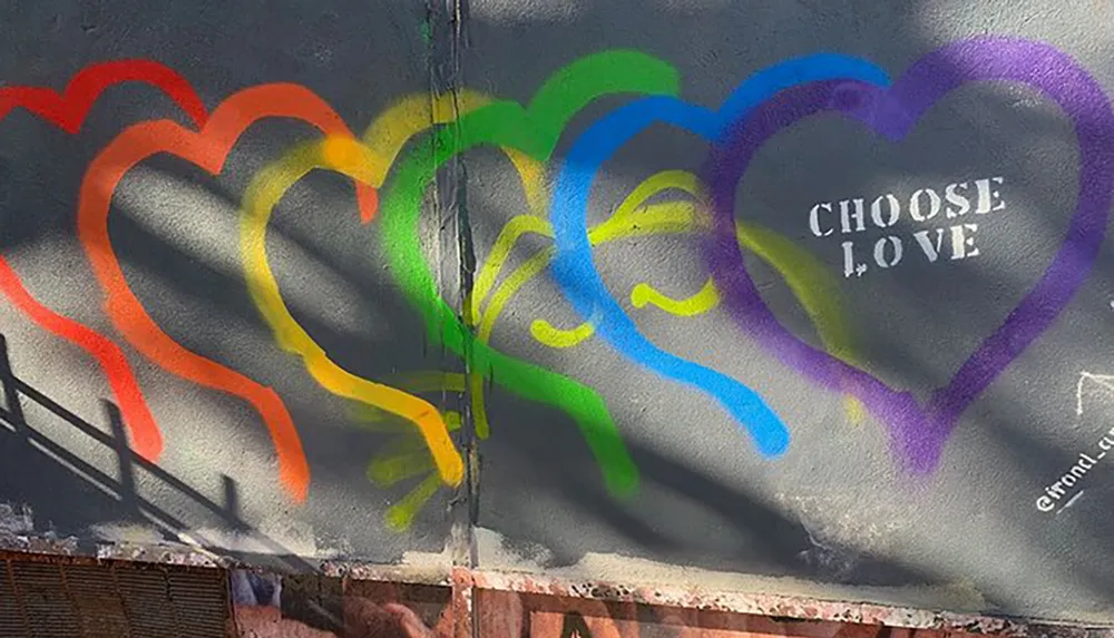 This image shows a colorful street art piece with a sequence of overlapping hearts in rainbow colors with the phrase CHOOSE LOVE painted in the center of the last heart