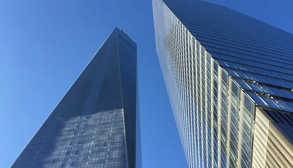 Two towering skyscrapers reach into a clear blue sky showcasing their reflective glass facades