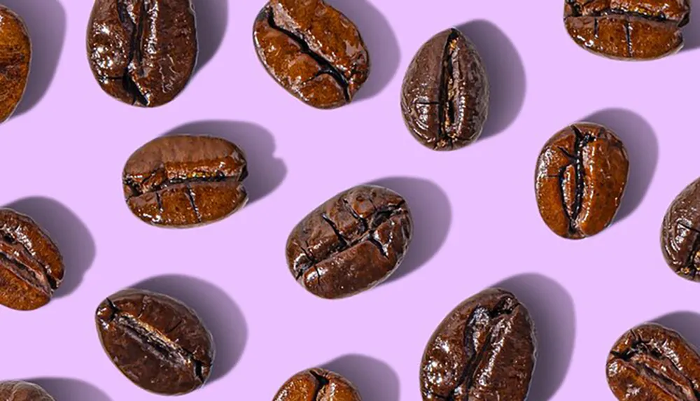 This image shows multiple glossy coffee beans scattered against a purple background