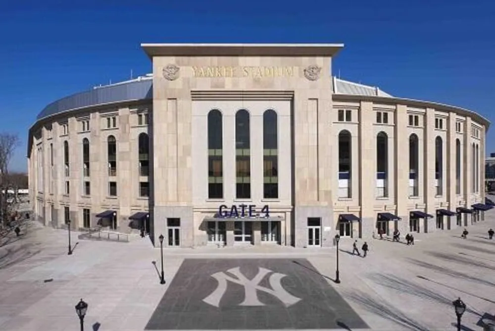 The image displays the exterior of Yankee Stadium with Gate 4 visible and a few people walking nearby