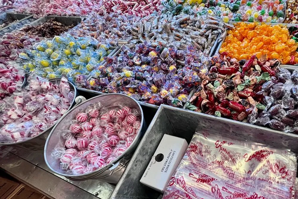 The image showcases a colorful assortment of various candies arranged in bins potentially at a candy store or market