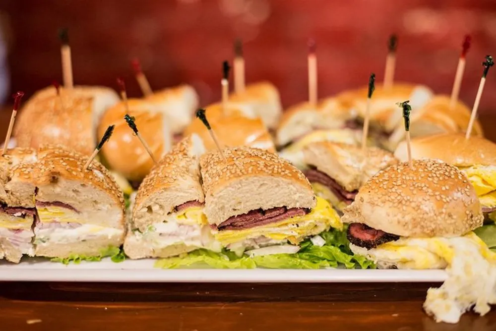 The image shows a platter of assorted cut sandwiches with toothpicks in them ready to be served at a gathering