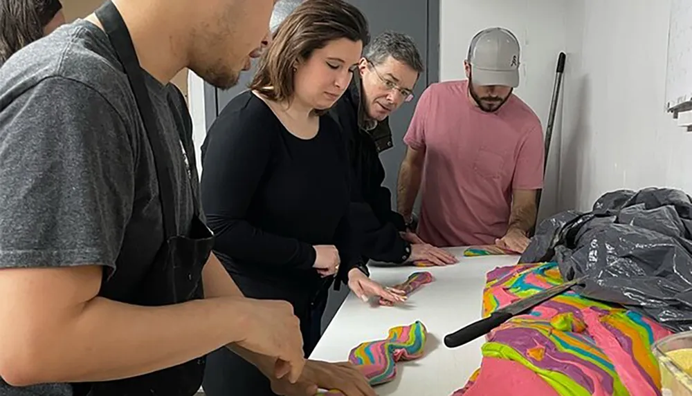 A group of focused individuals are inspecting or creating colorful swirled patterns on a table potentially engaging in an art or craft activity