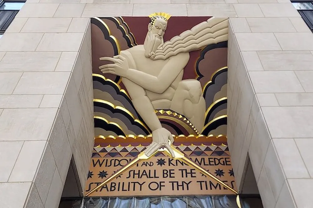 The image shows a large stylized bas-relief sculpture of a seated figure with rays and clouds in the background located above an entryway with the inscription Wisdom and Knowledge shall be the stability of thy times