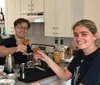 Two people are cheerfully toasting with cocktails in a home kitchen setting
