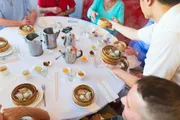 A waiter is serving dim sum to a group of people at a restaurant table covered with various foods and teaware.