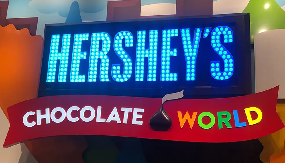 The image displays a colorful and illuminated sign for Hersheys Chocolate World