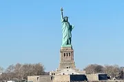 The image showcases the Statue of Liberty against a clear blue sky, symbolizing freedom and democracy.