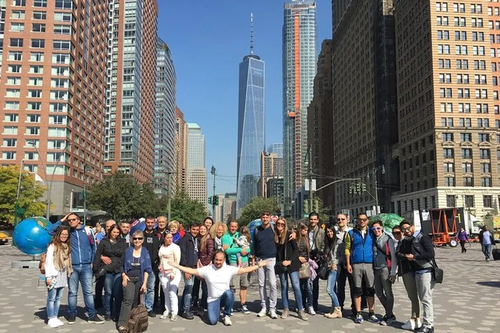 A group of people is posing for a photo on a sunny day with the One World Trade Center in the background
