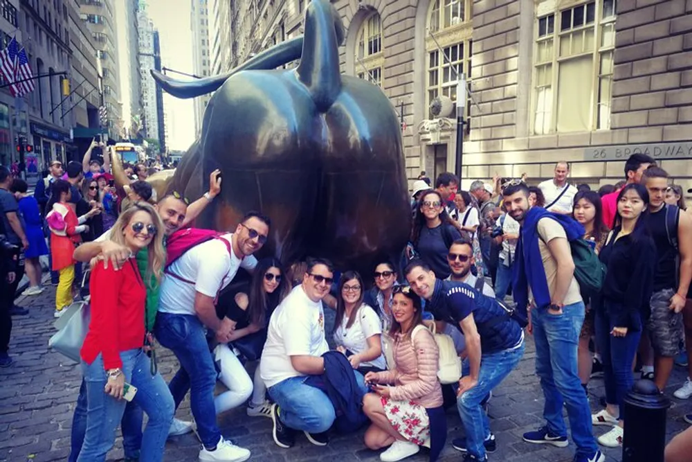 A group of people is posing for a photo with the Charging Bull sculpture in New York City