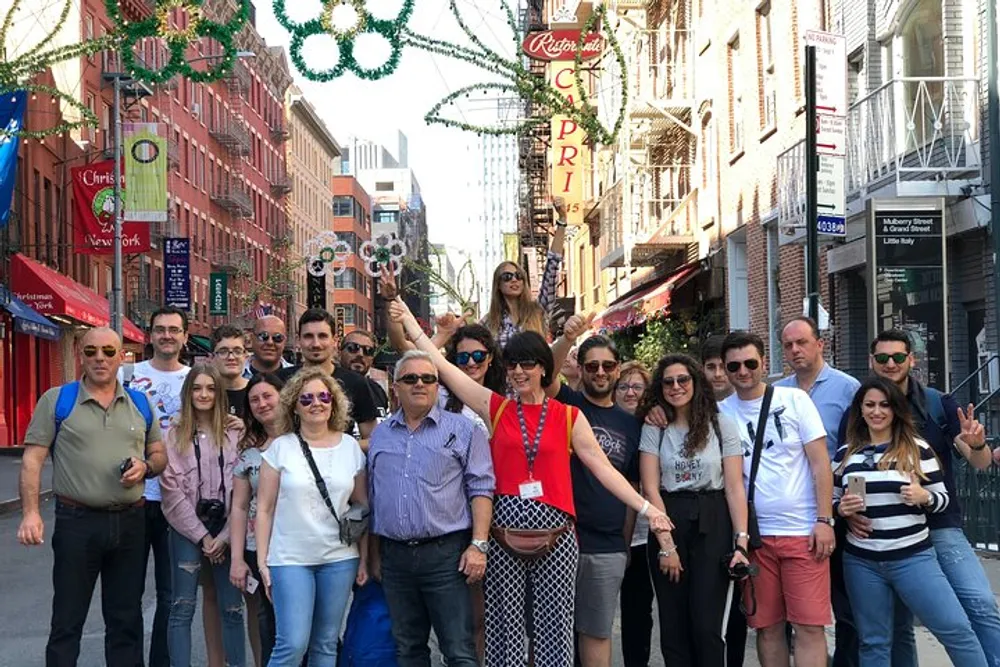 A diverse group of people is posing for a photo on a street adorned with festive decorations