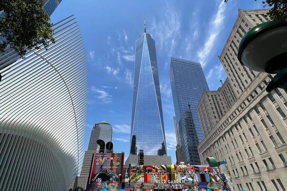 The image captures a clear day in an urban landscape showcasing a mix of modern architecture including a prominent glass skyscraper surrounded by other buildings and a colorful billboard at street level