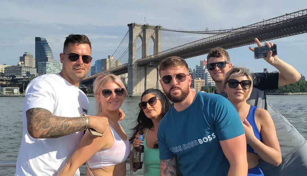 A group of people posing for a photo with the Brooklyn Bridge in the background