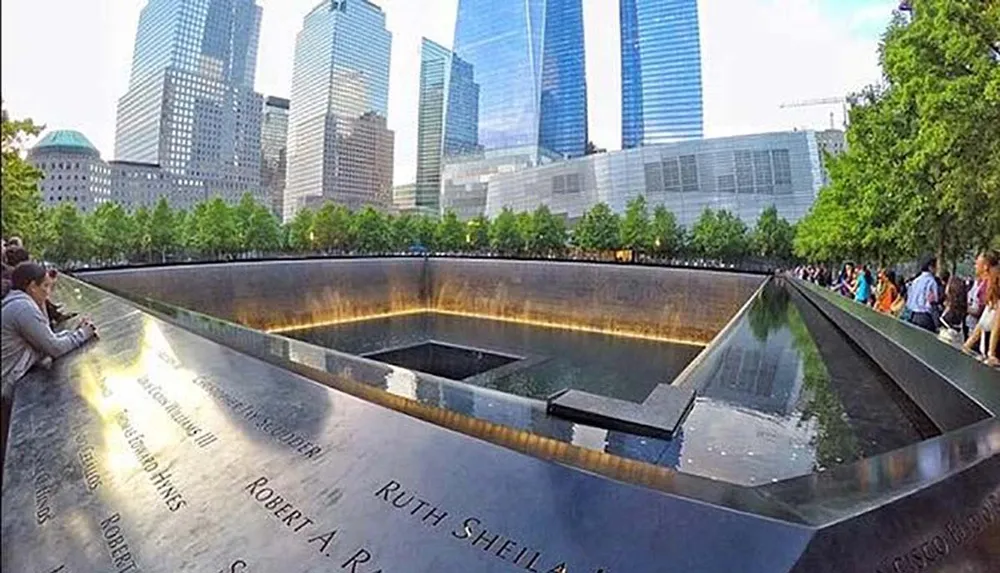 Visitors are gathered around the reflecting pool at the 911 Memorial in New York City which commemorates the victims of the September 11 attacks with names inscribed around the perimeter