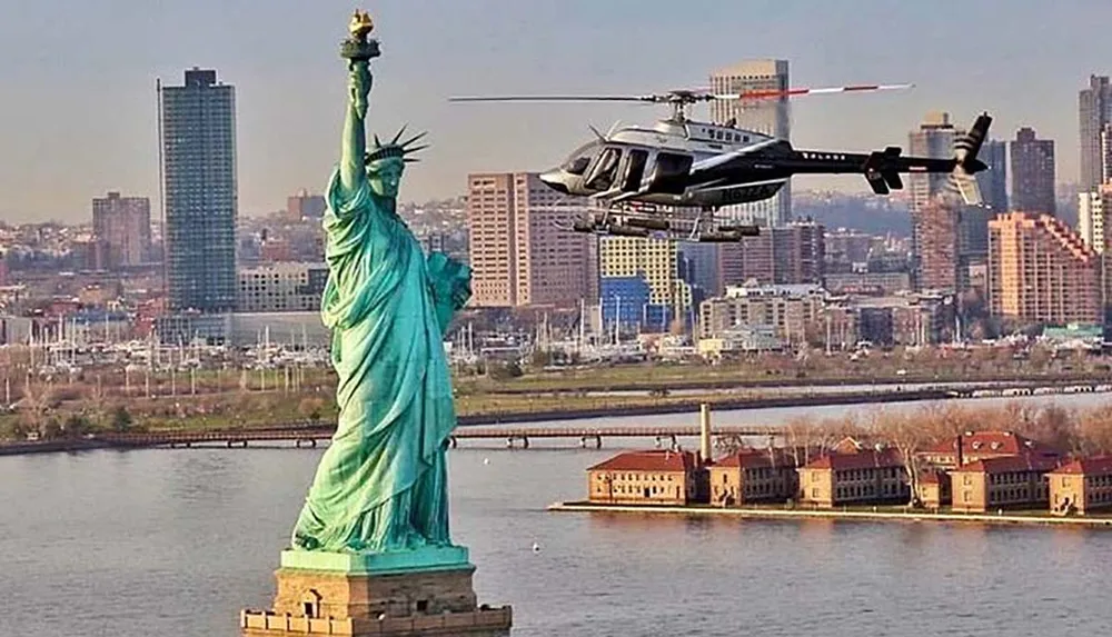 The image shows the Statue of Liberty with a helicopter flying in the foreground against a backdrop of New York Citys skyline