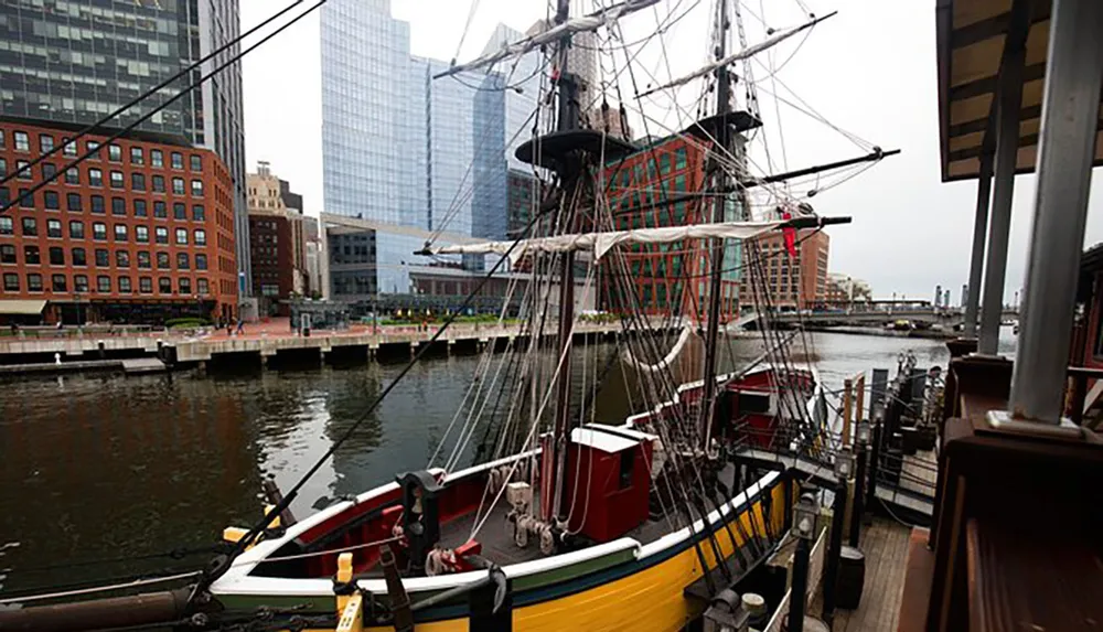A historical tall ship is docked in a modern urban waterfront setting blending maritime history with contemporary city architecture