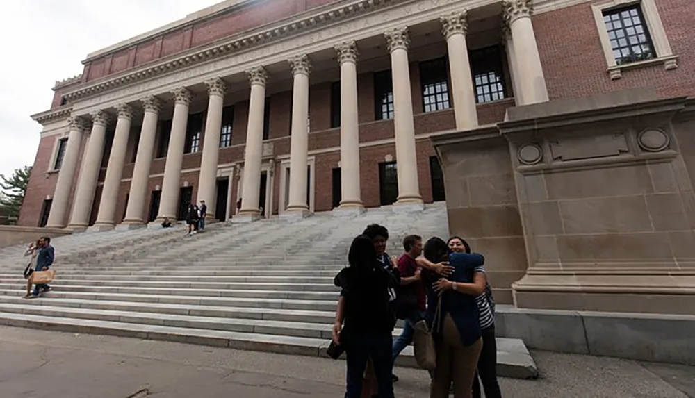 People are seen in front of a grand building with large columns and steps engaging in various activities such as taking photos walking and having conversations