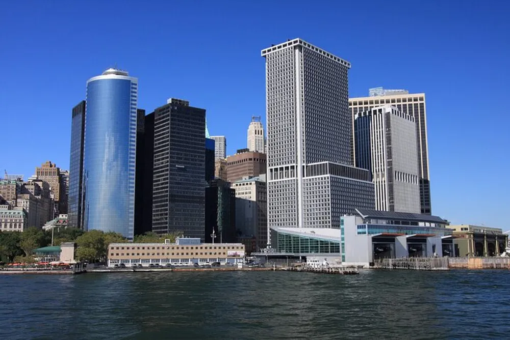 The image shows a view of a waterfront with modern high-rise buildings against a clear blue sky