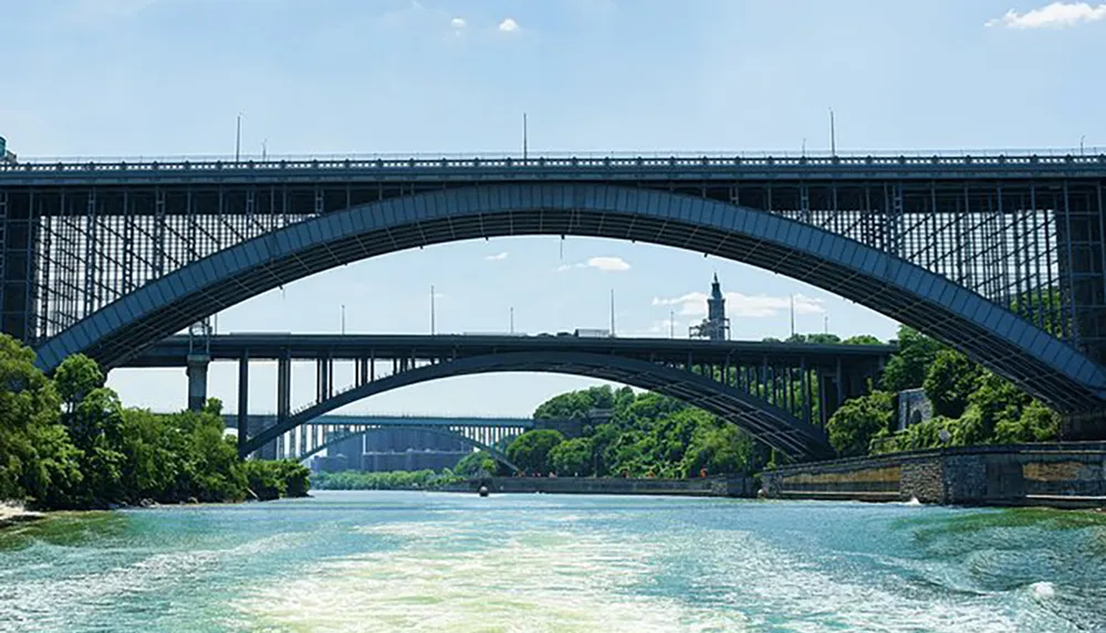 The image displays a multi-level bridge system with arches crossing over a body of water showcasing a series of bridges receding into the distance under a blue sky