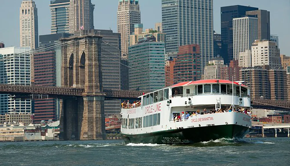 A sightseeing boat cruises near the Brooklyn Bridge with the backdrop of the Manhattan skyline