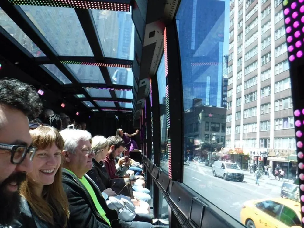 Passengers inside a bus with large windows and LED lighting observe the city views outside