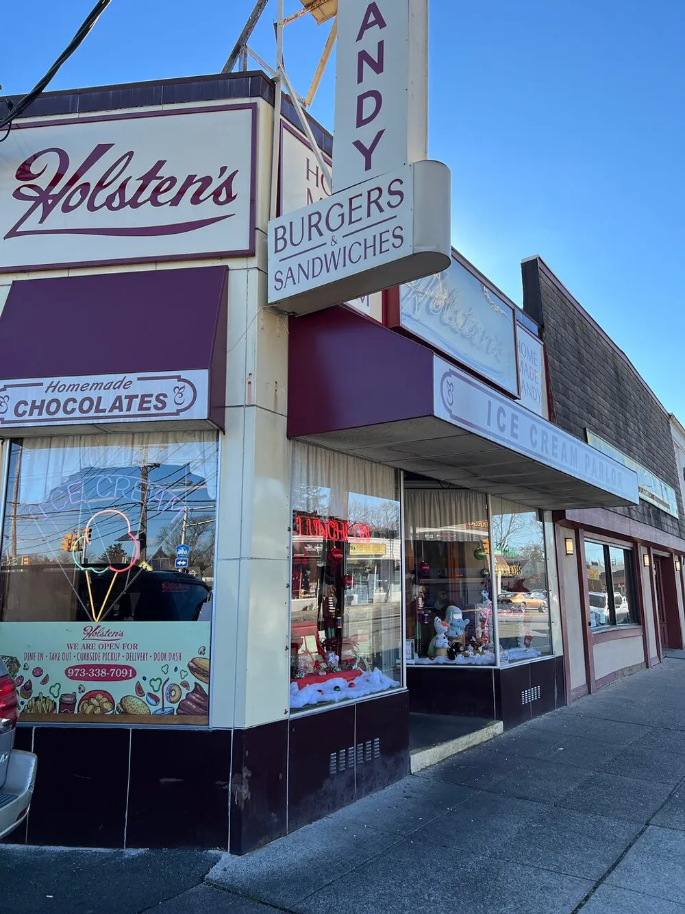 The image shows the storefront of a classic-looking diner or confectionery featuring signs for homemade chocolates burgers sandwiches and an ice cream parlor