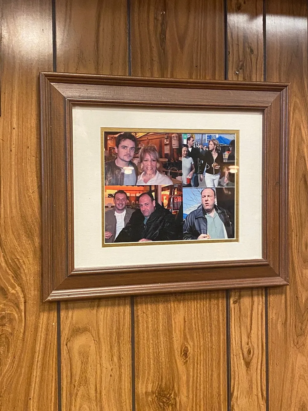 The image shows a wooden-framed collage featuring several smaller photographs of people hung on a wood-paneled wall