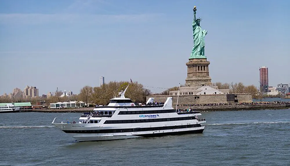 A City Cruises boat sails near the Statue of Liberty under a clear blue sky