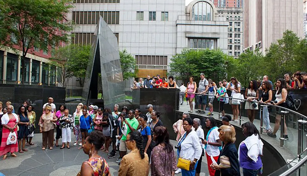 People are gathered around an urban outdoor memorial possibly waiting in line or reflecting