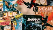 The image is a colorful collection of various comic books, including titles from Marvel and DC featuring popular superheroes like Batman and the Fantastic Four.