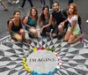 Five individuals are posing for a photo around the iconic Imagine mosaic memorial in Central Park New York City