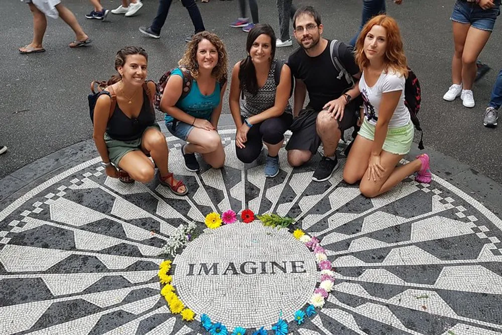 Five individuals are posing for a photo around the iconic Imagine mosaic memorial in Central Park New York City