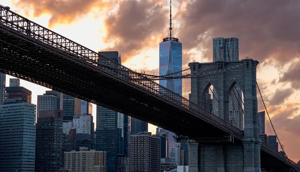 The image features the Brooklyn Bridge foregrounding the New York City skyline with a dramatic sunset in the background