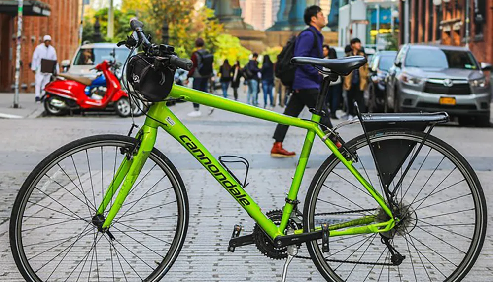 A bright green Cannondale bicycle is prominently displayed in an urban setting with pedestrians and vehicles in the background