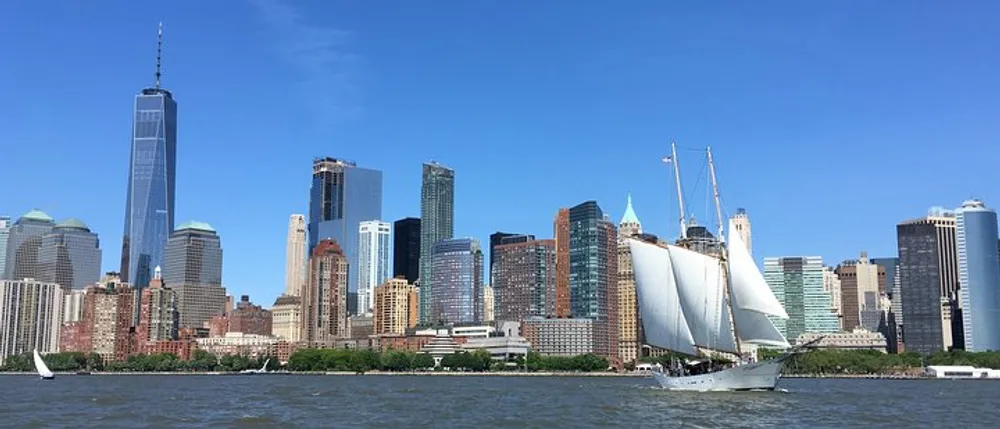 A sailboat cruises in front of the Lower Manhattan skyline with the One World Trade Center standing tall in the background