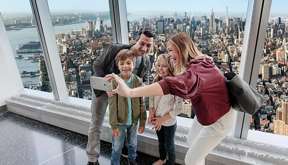 A family is taking a selfie with a smartphone inside a high-rise building overlooking a panoramic cityscape