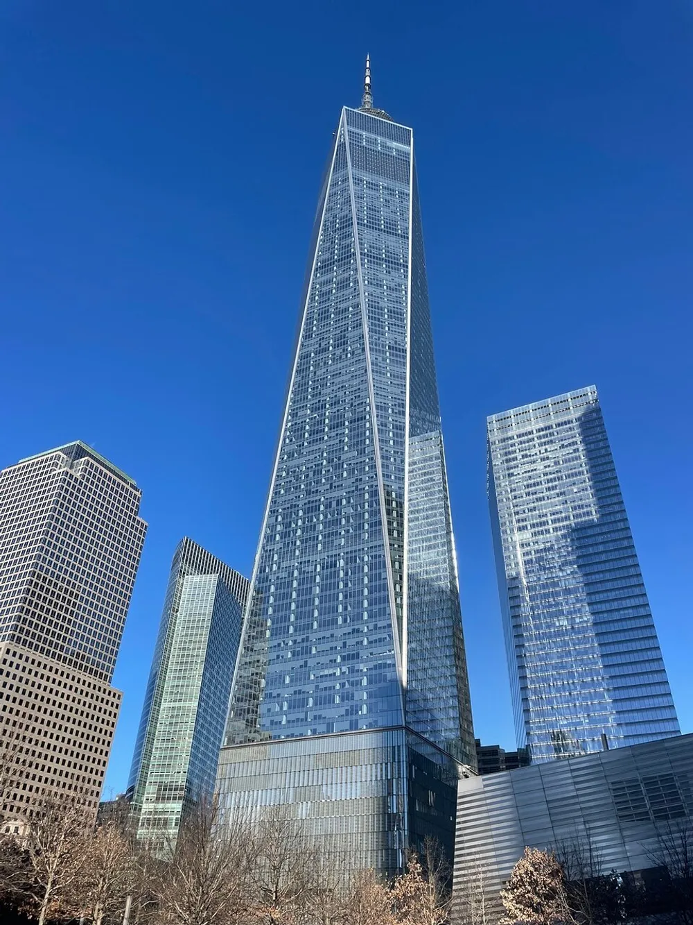 This image shows a tall striking skyscraper dominating the skyline against a clear blue sky surrounded by several other high-rise buildings