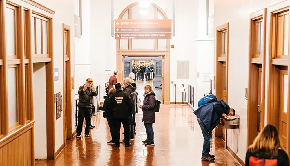 Visitors are engaged in various activities in a spacious museum hallway with informative signs visible overhead