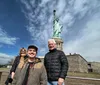 Three people are posing for a photograph with the Statue of Liberty in the background