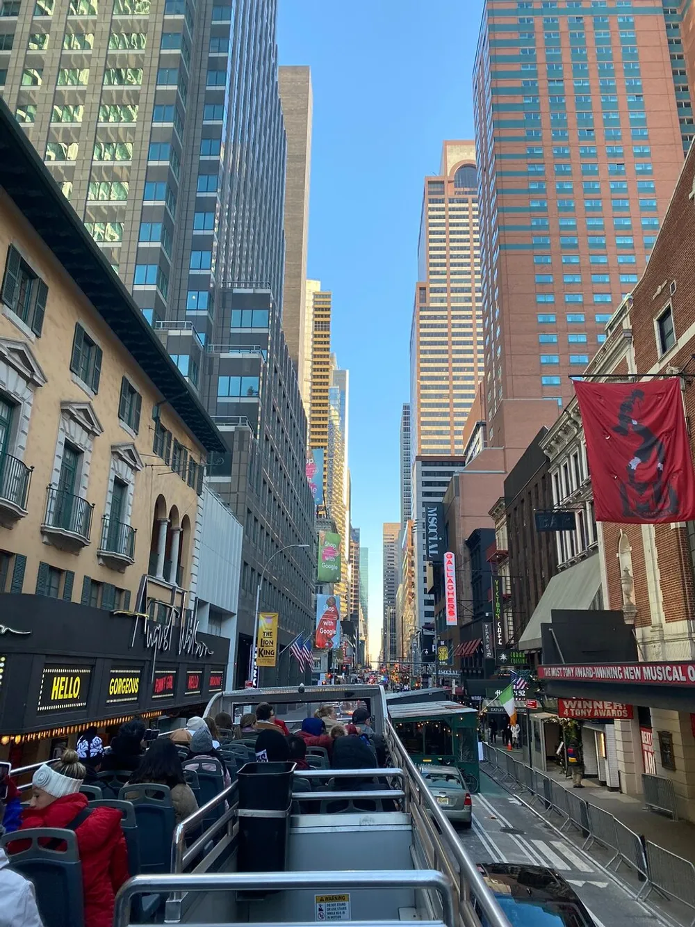 Tourists are enjoying a double-decker bus tour amidst the towering skyscrapers and bustling city life of a vibrant urban downtown