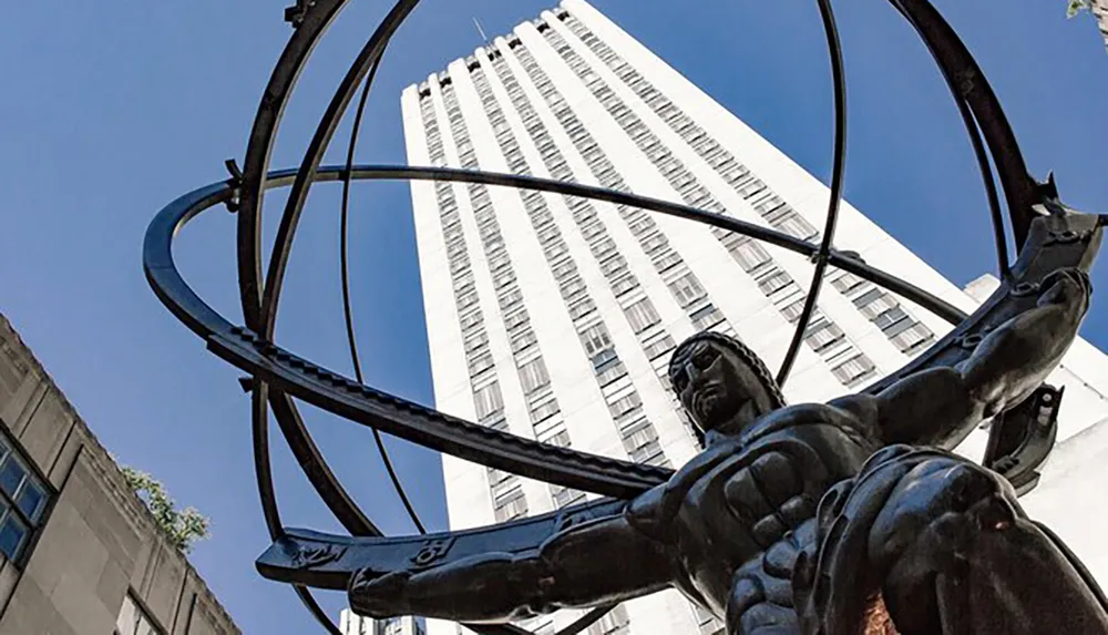 A statue of Atlas carrying the celestial spheres on his shoulders is positioned in front of a towering skyscraper